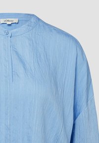 Chemise bleu clair texturée avec de subtiles rayures verticales, un col rond, un bouton unique au niveau de l'encolure, et une étiquette de la marque s.Oliver.