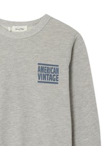 Sweatshirt gris clair à col rond avec le texte bleu "AMERICAN VINTAGE" imprimé sur la poitrine gauche.