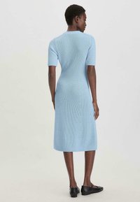 Lichtblauwe gebreide jurk tot de knie met korte mouwen, aansluitend lijfje en iets uitlopende rok. Eenvoudig ontwerp met een ribbelstructuur.