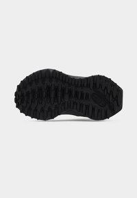 Semelle extérieure de basket noire affichée, présentant des motifs texturés et des rainures profondes pour la traction, fabriquée en matériau en caoutchouc durable.