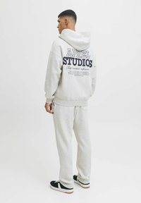 Lys grå hættetrøje med marineblå typografi på ryggen, parret med matchende grå svedbuks. Har en afslappet pasform og ribbede manchetter.
