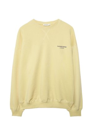 Felpa gialla chiaro con scollo a girocollo, polsini e orlo a coste, con piccole scritte nere "Portobello Sundays LONDON" sul petto a sinistra.