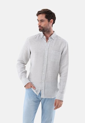 Helles graues Hemd mit Knopfleiste aus strukturiertem Stoff, ausgestattet mit einer Brusttasche und dezenten Mustern, kombiniert mit hellblauen Jeans.