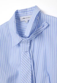 Camicia a righe blu chiaro e bianca con colletto a punta, chiusura con bottoni e dettaglio della cravatta. Realizzata in un tessuto morbido.