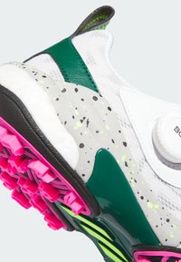Vit sportskor med gröna och svarta detaljer, spräcklig grå mellansula, rosa klackar och ett säkert spännlås.