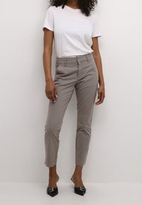 Beige, op maat gemaakte broek met een slim fit, voorzien van riemlussen, een gladde textuur en een cropped lengte, gecombineerd met een eenvoudig wit t-shirt.