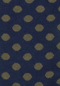 Marineblaues Gewebe mit einem sich wiederholenden Muster aus hellgrünen Punkten. Die Textur ist gestrickt und weist gleichmäßig verteilte kreisförmige Designs auf.