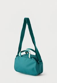 Τυρκουάζ ορθογώνια τσάντα ώμου με διπλές λαβές που έχουν λευκές ρίγες και ρυθμιζόμενο μακρύ ιμάντα ώμου, σε λευκό φόντο.