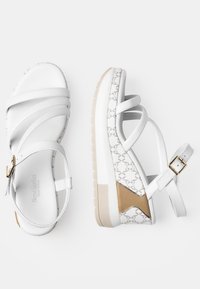 Sandali platform bianchi con cinghie incrociate, pannello laterale testurizzato con un motivo, dettagli in metallo dorato e una suola liscia e imbottita.