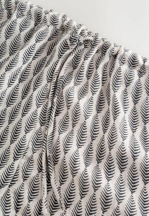 Bavlněná látka s opakujícím se černým vzorem kapradí na světlém pozadí. Má shromážděný pas s nastavitelnými šňůrkami.