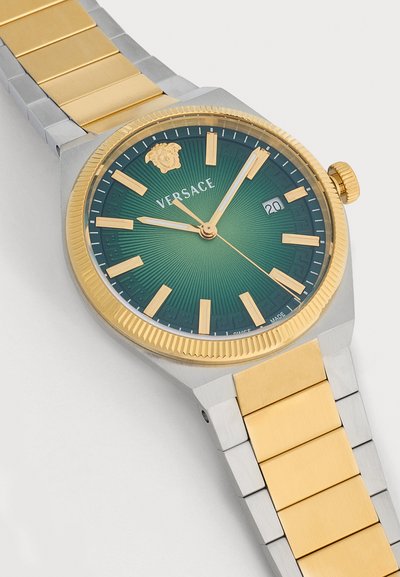 Montre-bracelet de luxe avec bracelet métallique en or et argent, cadran vert, index dorés, logo Versace et affichage de la date indiquant le 20.