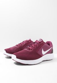 Baskets de sport marron avec une tige en mesh, des accents blancs et une semelle texturée. Design à lacets avec un col rembourré pour le confort.