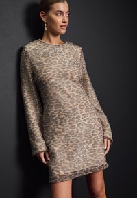 Rochie lungă cu imprimeu de leopard, confecționată dintr-un material strălucitor. Are un guler rotund și o siluetă ușor evazată. Accentele sunt decorative cu paiete.