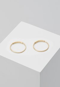 Pendientes de aro de oro con un diseño delgado y suave. Cada pendiente es circular y abierto, con un acabado pulido sobre un fondo blanco.