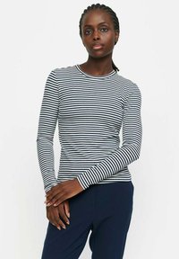Langärmliges gestreiftes Oberteil in Marineblau und Weiß, mit Rundhalsausschnitt, slim Fit und weichem Stoff, kombiniert mit dunkelblauen Hosen.