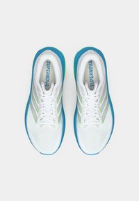 Λευκά αθλητικά παπούτσια με επάνω μέρος από διαπνέον διχτυωτό υλικό, πράσινες και ασημί ρίγες και μπλε σόλα. Διαθέτουν επίπεδα κορδόνια και διάτρητη περιοχή στα δάχτυλα.