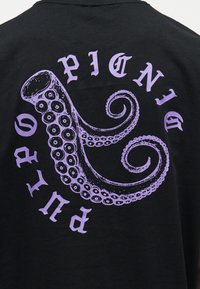 Material negru cu un grafic de tentacul de caracatiță violet, înconjurat de cuvântul „Pictning” scris cu litere în stil gotic.