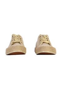 Beige snörda skor med gyllene snören, vävda jutesulor och en slät canvasöverdel. Har en rund tå och en minimalistisk design.