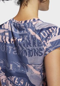 Athletické tričko s krátkým rukávem v kombinaci tmavě modré a růžové barvy s potiskem textu. Hladká látka s kulatým výstřihem a prošitými okraji.