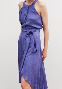 Purple dress made of textured fabric, featuring a sleeveless halter neck, a twisted waist tie, and an asymmetrical hemline.