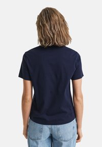 T-shirt en coton bleu marine avec un col rond et des manches courtes, présenté de dos, avec une texture lisse et une coupe décontractée.