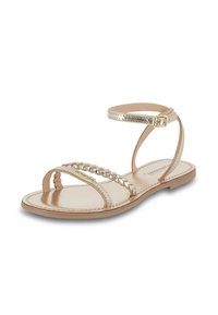 Sandale plate dorée avec un design de sangle tressée, boucle autour de la cheville et semelle intérieure lisse beige. Fabriquée en matériaux synthétiques.