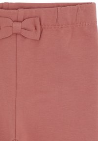 Weicher, pinker Stoffbund mit einem kleinen genähten Schleifendetail und elastischem Abschluss an einer Kinderhose oder Leggings.