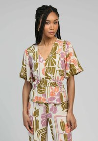 Blouse légère à motif floral avec un col en V et une taille élastique, présentant des nuances de rose, de vert et de crème ; manches courtes en ballon.