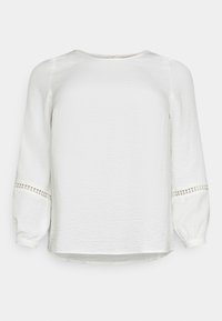 Blusa bianca a maniche lunghe realizzata in tessuto testurizzato, con scollatura tonda e dettagli in pizzo sui polsini.