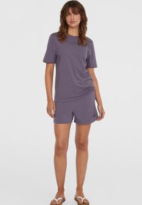 Paarse katoenen T-shirt met korte mouwen en een relaxte pasvorm, gecombineerd met bijpassende shorts. Beide hebben subtiele branding in de stof.