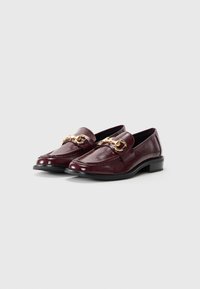 Mocassins en cuir verni bourgogne avec un accent décoratif en chaîne dorée, bout rond et petit talon carré. Texture lisse avec une finition brillante.