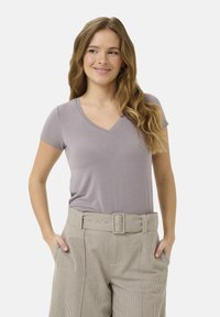T-shirt à col en V avec des manches courtes en tissu lavande doux, associé à un pantalon taille haute à rayures claires et une ceinture assortie.