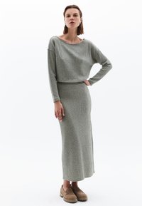 Ensemble en deux pièces côtelé de couleur gris clair, comprenant un haut à manches longues court et une jupe ajustée longue. Tissu texturé, design simple.
