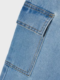 Svetlo modra denim tkanina s našitjem žepom in kontrastnim oranžnim šivom, ki prikazuje gladko teksturo in tkan vzorec.