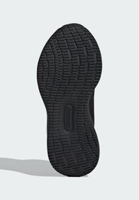 Semelle extérieure de sneaker noire avec une surface en caoutchouc texturée, dotée d'un motif de semelle pour l'adhérence et d'un élément de design central lisse.