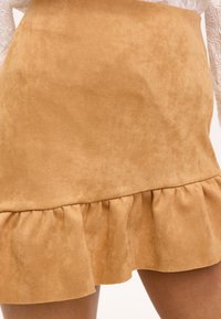 Bruine suède mini-jurk met een gerimpelde zoom, met een gladde textuur en een rechte vorm, ontworpen voor een aangesloten silhouet.