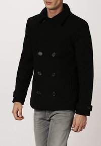 Cappotto doppiopetto nero realizzato in lana, con colletto a pistagna, due tasche frontali e polsini con bottoni.