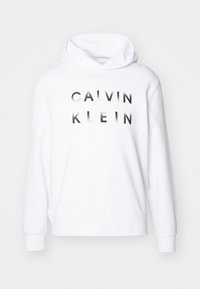 Bela kapuca sweatshirt z napisom "CALVIN KLEIN" v črni barvi. Narejena iz mehkega materiala, s sproščenim fitom ter rebrastimi manšetami in robom.