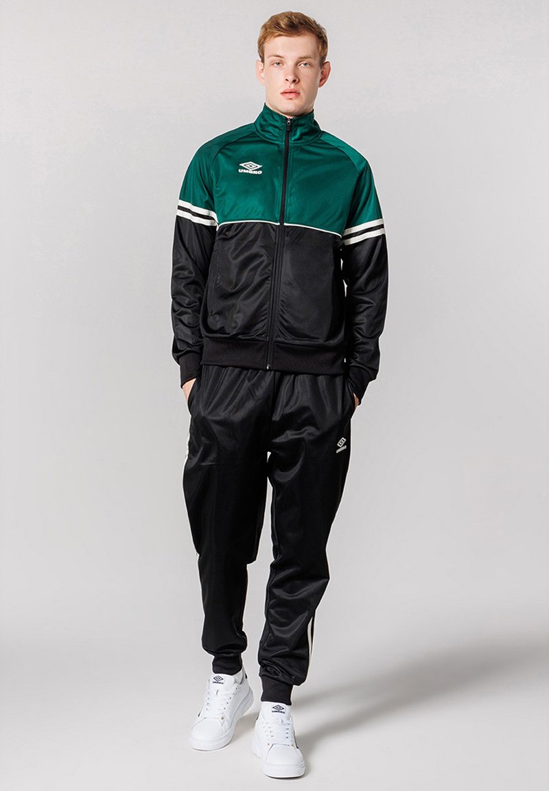 Tracksuit in black and green with white stripes. Jacket features zip closure, ribbed cuffs; pants have elastic waistband and side pockets.