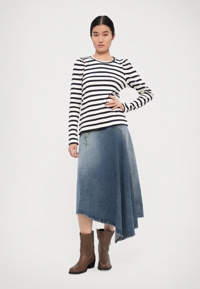 Stripet langermet skjorte i hvit og marineblå, kombinert med et denimskjørt med asymmetrisk skjæring som har blomsterbroderi, og brune ankelstøvler.