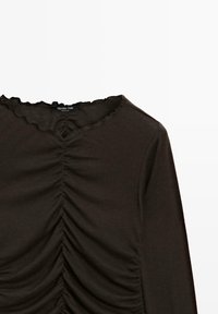 Maglietta nera a maniche lunghe con una texture arricciata sul davanti, colletto ondulato e materiale in cotone morbido. Etichetta del marchio visibile.