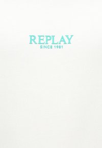 Λευκό πουκάμισο με γαλάζιο κείμενο «REPLAY» και «SINCE 1981». Ομαλή υφή υφάσματος με απλό, καθαρό σχέδιο.