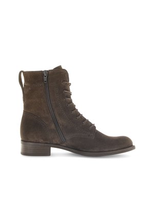 Bottine en suède marron, avec un bout rond, des lacets à l'avant, une fermeture éclair sur le côté et un petit talon empilé. Coutures détaillées sur les côtés.