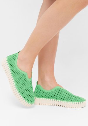 Groene instapschoenen hebben een geperforeerde mesh bovenkant met een golvend patroon en een dikke roomkleurige rubberen zool, wat zorgt voor een lichtgewicht ontwerp.