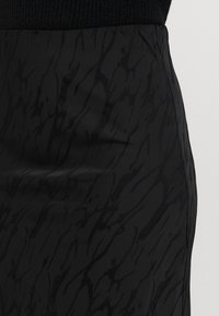 Melna svārku konstrukcija ar gludu, teksturētu virsmu un niansētu, abstraktu rakstu. Pieguļošs dizains, vidēja garuma griezums. Malas ir tīras.