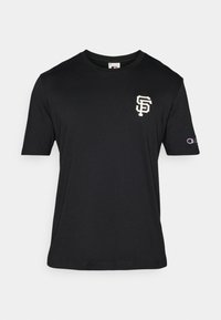 Svart kortermet t-skjorte laget av bomull, med en kremfarget brodert "SF"-logo på brystet og en liten Champion-logo på ermet.
