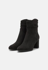 Schwarze Wildleder-Boots bis zum Knöchel mit einem lockeren Design, spitzen Zehen und einem klobigen Absatz. Mit einem seitlichen Reißverschluss für einfaches An- und Ausziehen.