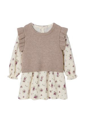 Beiger Pullover mit Rüschenschultern, über einem cremefarbenen Kleid mit floralen Mustern, kleinen lila Rosen und strukturiertem Stoff getragen. Lange, gepuffte Ärmel.