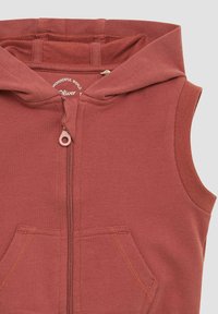 Rustfarbenes ärmelloses Hoodie mit Reißverschluss, zwei vorderen Taschen und weichem Stoff. Mit Kapuze und sichtbaren Nähten.