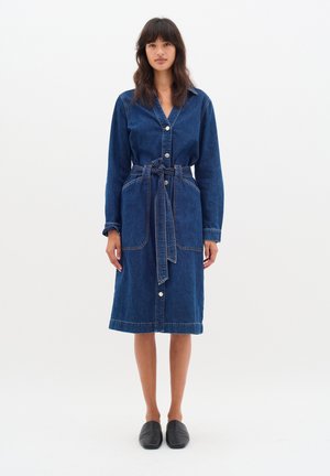 Abito camicia in denim con colletto, maniche lunghe, vita con cintura, chiusura frontale a bottoni e due tasche; colore blu con cuciture in contrasto.